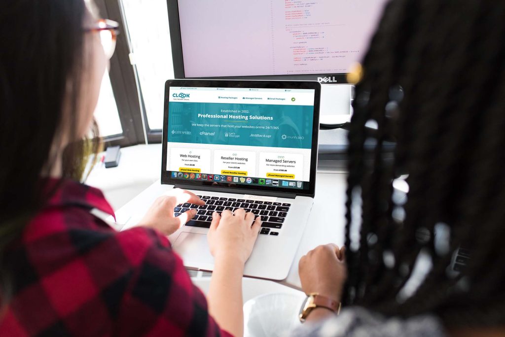 Two web developers reviewing Clook Internet's website on a computer screen